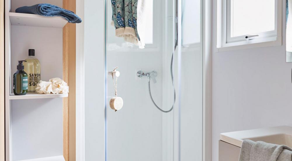 Salle de bain équipée d'un lavabo, d'une douche et sèche serviettes